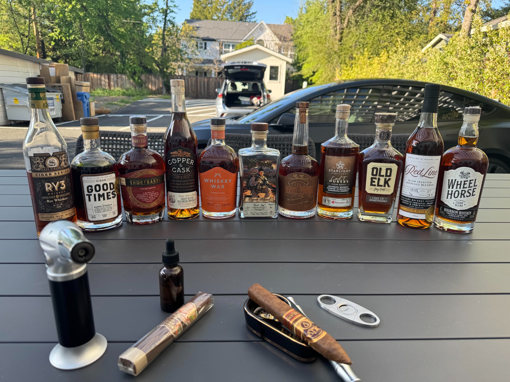 A lineup of cigar-finished whiskeys with cigars